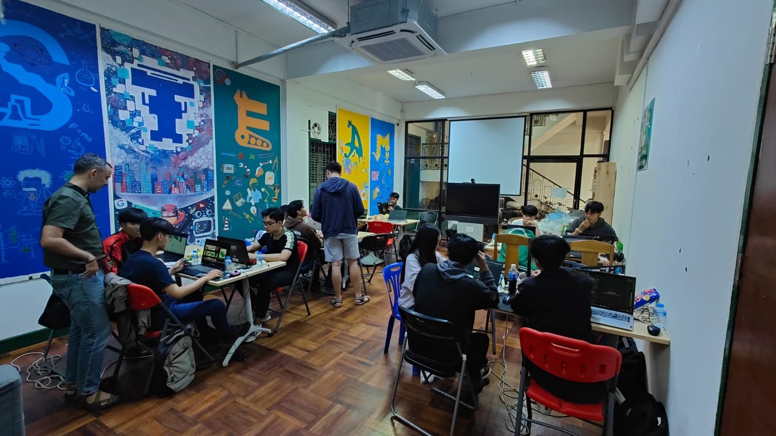 Builders working together on laptops in the MBX Robotics community workshop space