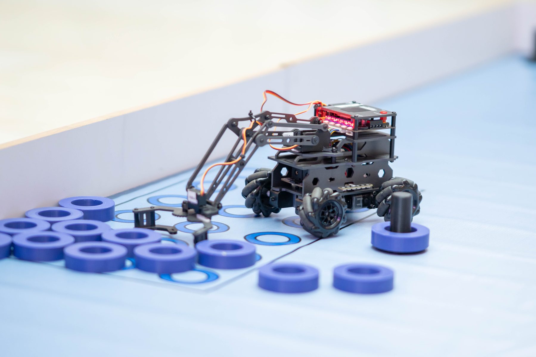 Close-up of a robot arm and mecanum wheel robot used in a build challenge