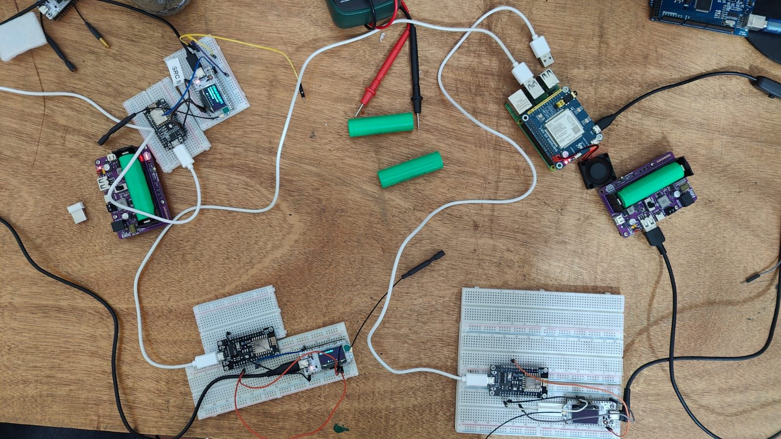Workbench covered in microcontroller boards, breadboards, batteries, and test equipment from the MBX Electronics Shop
